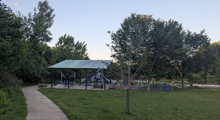 A green-roofed pavilion beside a playground, seen from the park path